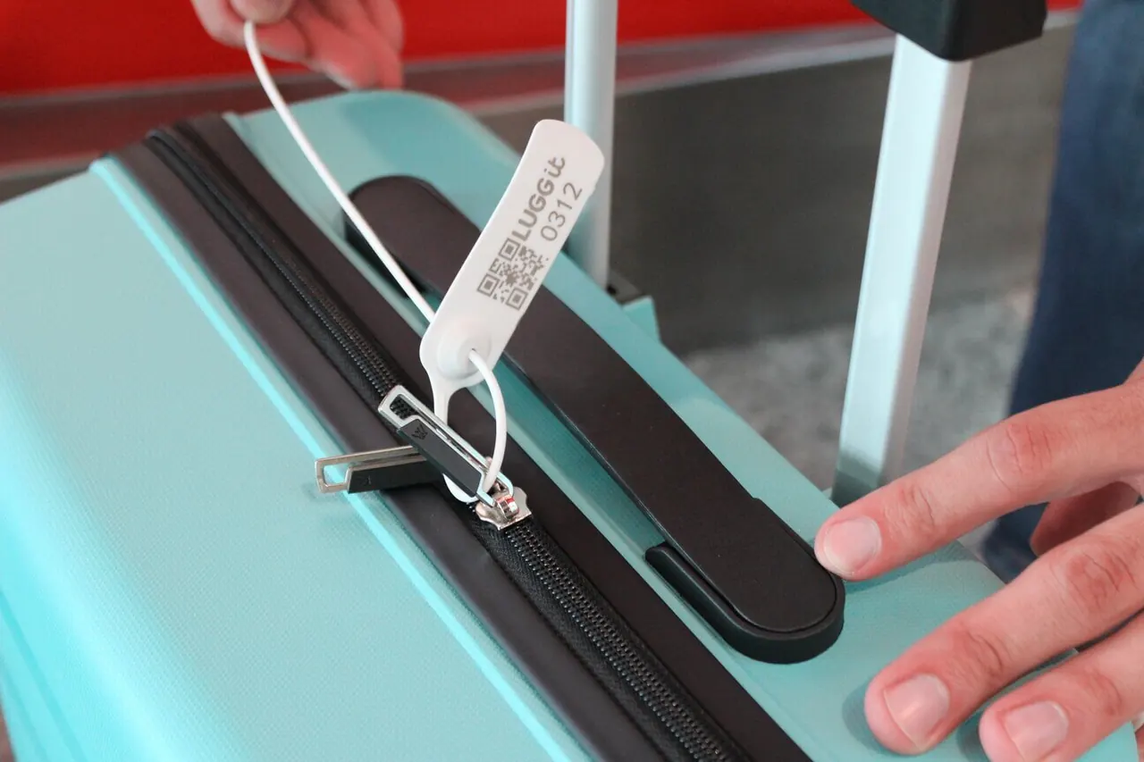 A LUGGit identification seal being attached to a suitcase at collection.