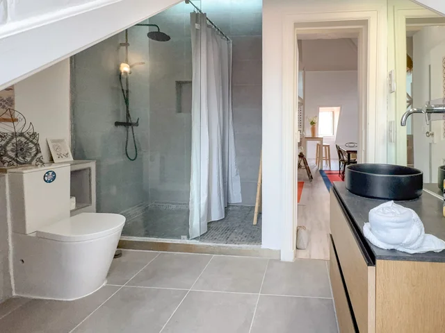 Bathroom with a large shower, white sanitary ware and a black stone basin