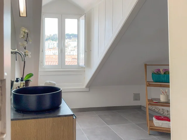 Bathroom with a black basin and dormer view of São Jorge Castle