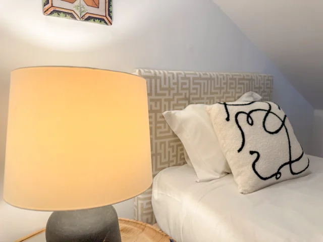Lamp and Picasso-style cushion against a Greek-key headboard