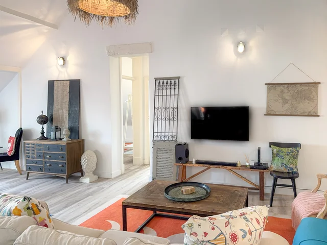 Living room with eclectic decor — boho pendant lamp, antique blue dresser, world map and floral cushions