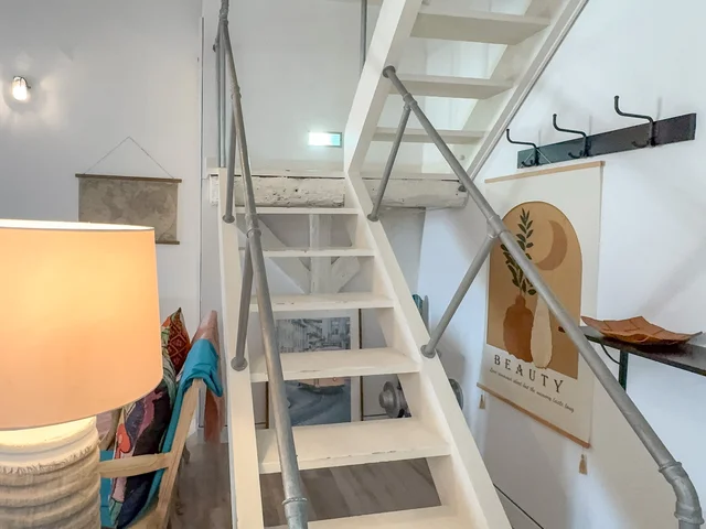 Steel staircase leading to the mezzanine, with Picasso-style art and cushions